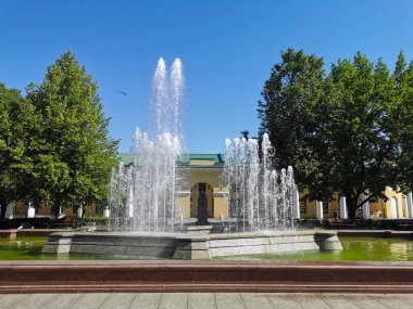 Gosin Avlusu yakınlarında bir çeşme, granit kâsesi Kronshlot şehrindeki Kronshlot kalesinin dış hatlarını andırıyor mavi bulutsuz gökyüzünün arka planına karşı..