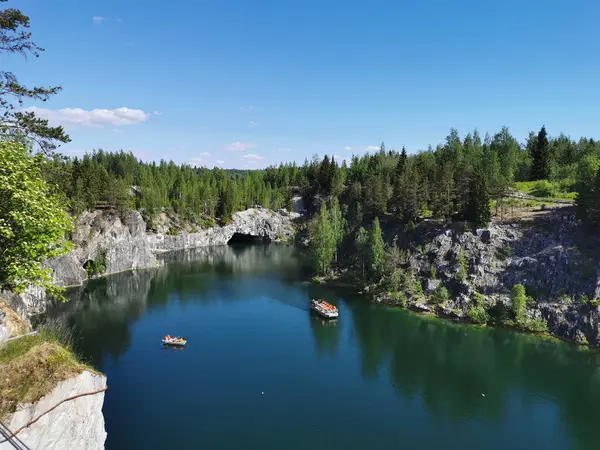 Ruskeala Dağ Parkı 'ndaki Mermer Kanyon' un turkuaz suyunun gözlem güvertesinden gökyüzünün yansıması ve güneşli bir yaz gününde ağaçların görüntüsü..