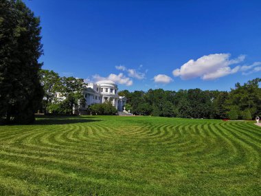 Güneşli bir yaz gününde Elaginoostrovsky Sarayı 'nın yanındaki parkta dalgalı çizgilerle süslenmiş bir bahçe..