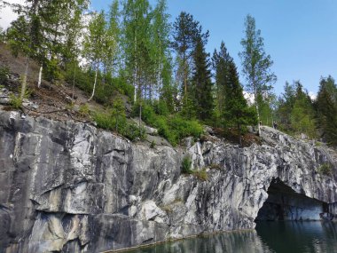 Güneşli bir yaz gününde Ruskeala dağ parkında, mağara suyundan ve ağaçların yetiştiği su basmış Mermer Kanyon 'un bir bölümünden manzara.