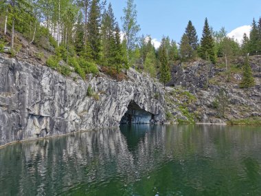 Güneşli bir yaz gününde Ruskeala dağ parkında, mağara suyundan ve ağaçların yetiştiği su basmış Mermer Kanyon 'un bir bölümünden manzara.