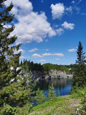 Güneşli bir yaz gününde gökyüzünü ve kayaları yansıtan Ruskeala Dağ Parkı 'ndaki Mermer Kanyon' un kayaları ve zümrüt suyu..
