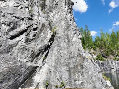 Güneşli bir yaz gününde Ruskeala Dağ Parkı 'ndaki su basmış Mermer Kanyon' un dik yamacındaki sudan manzara.