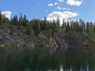 Güneşli bir yaz gününde Ruskeala Dağ Parkı 'nda ağaçların yetiştiği su basmış Mermer Kanyon' un yanındaki yüzer platformdan bir manzara..