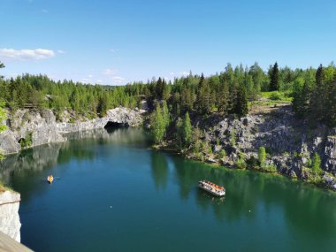 Ruskeala Dağ Parkı 'ndaki Mermer Kanyon' un turkuaz suyunun gözlem güvertesinden gökyüzünün yansıması ve güneşli bir yaz gününde ağaçların görüntüsü..