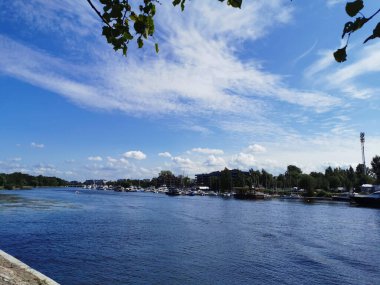 Krestovsky Adası açıklarında duran yatların görüntüsü. Güneşli bir yaz gününde bulutlu mavi gökyüzünün arka planına doğru giden bir tekne görülüyor.
