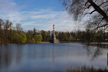 Catherine Park 'ın büyük gölünde yer alan Chesma sütunu ağaçlarla çevrilidir. Mavi gökyüzüne karşı.
