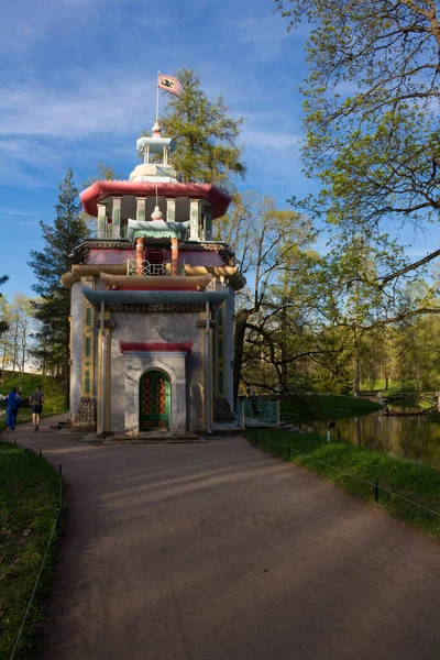 Path among the trees to the entrance to the Pavilion Chinese gazebo in Catherine Park against the blue sky.