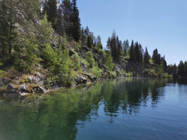 Güneşli bir yaz gününde Ruskeala Dağ Parkı 'ndaki Mermer Kanyon' un kayalık kıyıları ve zümrüt suyu manzarası.