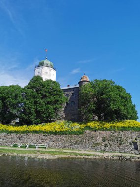 Mavi gökyüzünün arka planında tüylü bulutlar, Vyborg Kalesi ve Vyborg şehrindeki beyaz St. Olaf Kulesi..