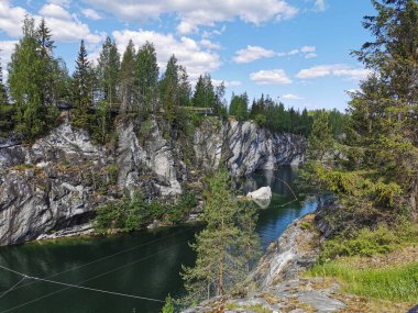 Kayalıkların en üst manzarası, Ruskeala Dağ Parkı 'ndaki Mermer Kanyon' un turkuaz sularında yüzen büyük taş ve kayıklar güneşli bir yaz gününde..