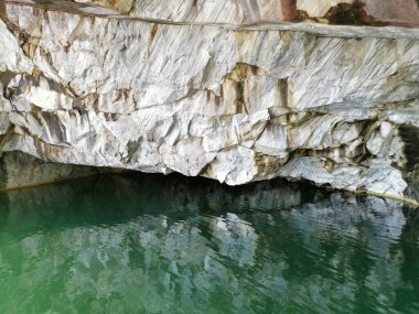 Ruskeala Dağ Parkı 'ndaki Mermer Kanyon' un zümrüt suyuna yansıyan mağara duvarı..