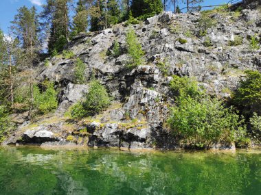 Güneşli bir yaz gününde Ruskeala Dağ Parkı 'ndaki Mermer Kanyon' un kayalık kıyıları ve zümrüt suyu manzarası.
