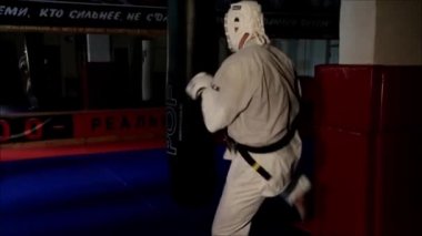 Beyaz kimonolu sporcu ve kask takan sporcu boks çantasıyla koridorda trenlere biniyor..