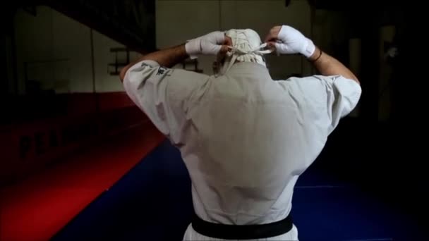 Un atleta en un kimono blanco lleva un casco protector sobre su cabeza. Artes marciales. — Vídeos de Stock