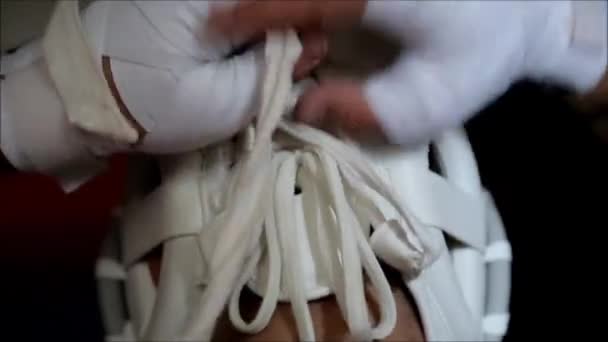 En idrottsman i vit kimono bär en skyddshjälm över huvudet. Kampsporter. — Stockvideo