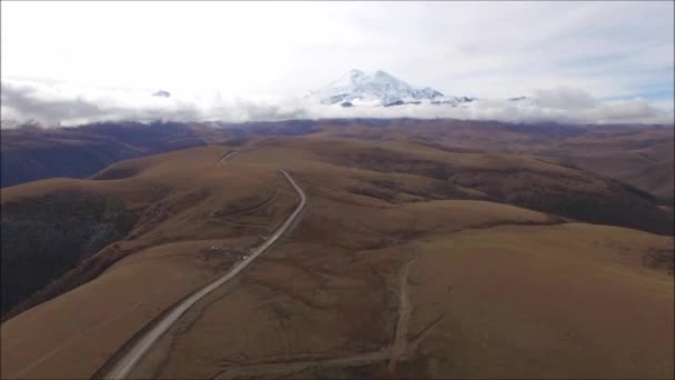 Un viaje por carretera a las montañas en un buen camino. Fotografía aérea y acción de cámara. — Vídeo de stock