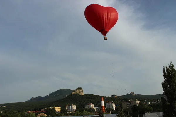 A red-hearted aerostat in the sky above the city. Romance. — Stock Photo, Image