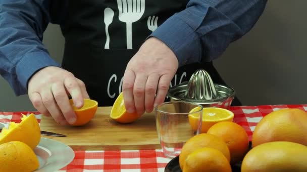 Un hombre hace jugo recién exprimido de naranjas y pomelo en un exprimidor hecho a mano — Vídeos de Stock