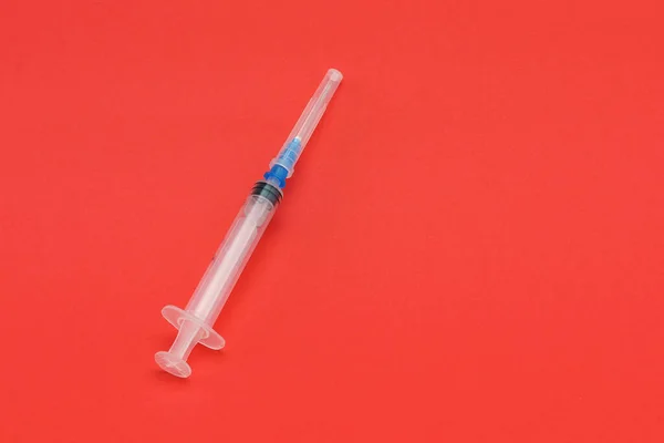 Une seringue jetable médicale est isolée sur un fond rouge. — Photo