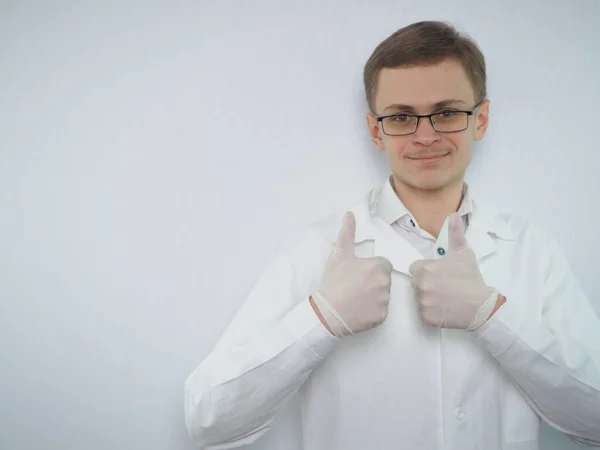 Porträtt av en ung man med europeiskt utseende i en vit medicinsk rock. En ung läkare i vit rock. Medicinsk student. — Stockfoto