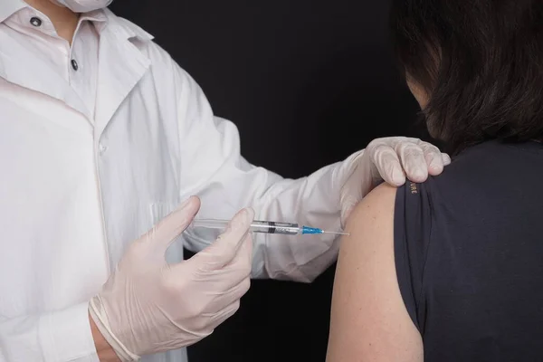 Nüfusun aşılanması. Bir sağlık çalışanı, bir doktor bir hastaya aşı yapar.. 