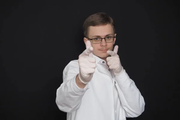 Potret seorang pemuda, seorang dokter dari Eropa yang tampil dalam jubah medis putih dengan latar belakang hitam. Seorang mahasiswa kedokteran. — Stok Foto
