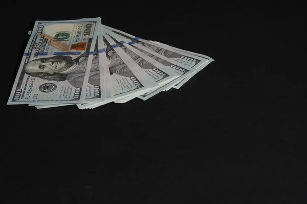 Az amerikai dollár. Papíralapú százdolláros bankjegyek fekete alapon. — Stock Fotó