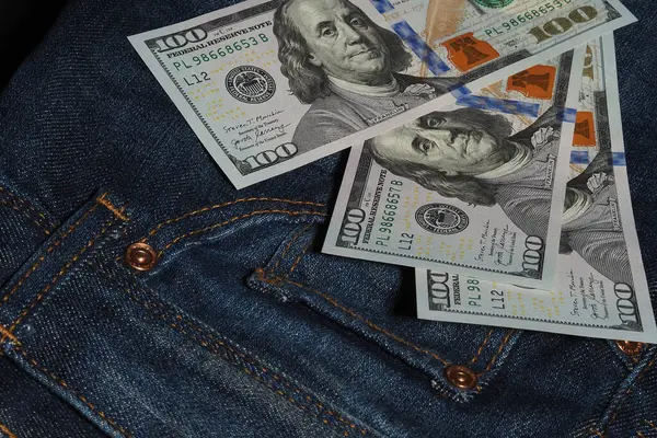 Hundred dollar American banknotes in the background of jeans. A symbol of America. Light industry and finance. — Stock Photo, Image