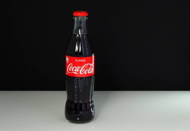 Logosu ve kırmızı kapağı olan klasik bir cam şişe olan Coca Cola siyah-beyaz arka planda izole edilmiştir..