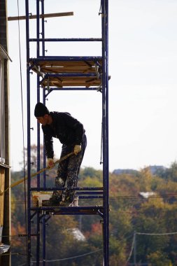 İnşaat. Bitirme işi. İnşaatçı işi bitirir, evin dış cephesini boyar.