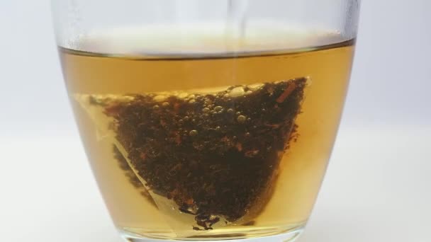 Preparare il tè nero in un bicchiere trasparente. La consistenza del tè e la colorazione dell'acqua. — Video Stock