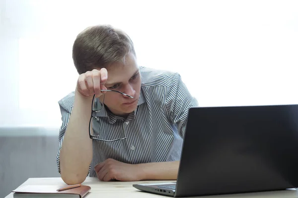 Trabalho remoto ou educação online. Um jovem com óculos atrás de uma tela de laptop. — Fotografia de Stock