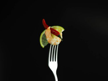 Limonlu karides ve çatallı kırmızı biber. Siyah arka planda deniz ürünleri atıştırması..