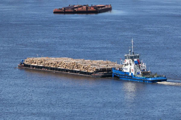 The barge transports cargo, timber logs along the river in summer.