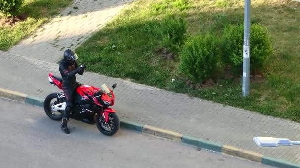 Motociclista en marcha y casco protector en una motocicleta roja, en la ciudad. — Vídeos de Stock