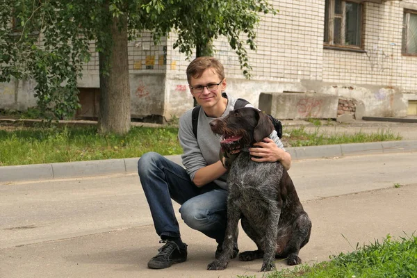 Un joven de aspecto europeo con un perro en la calle de la ciudad. — Foto de Stock