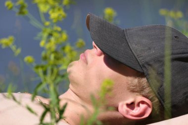 Yazın plajda şapkalı bir adam yatıyor. Yazın kumsalda güneşlen.. 