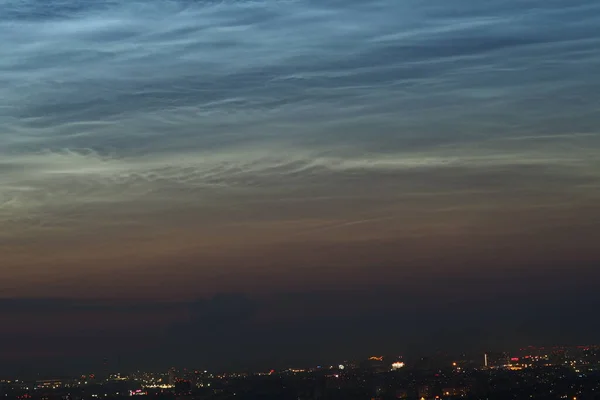 Noctilucent wolken aan de nachtelijke hemel boven de stad Prachtige natuurlijke achtergrond. — Stockfoto