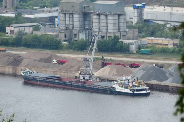 Nehirde mavna, nehir kıyısındaki bir mavnadan nehir kumu boşaltılıyor.