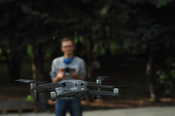 DJI-Drohnenpilot. Der junge Mann hält den Drohnen-Controller in der Hand und steuert die Mavic-Drohne. — Stockfoto