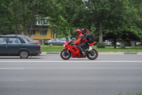 Şehir otobanındaki golde özel giysili motosikletçiler ve koruyucu kasklar. Kırmızı bir motosikletle. Yüksek kalite fotoğraf