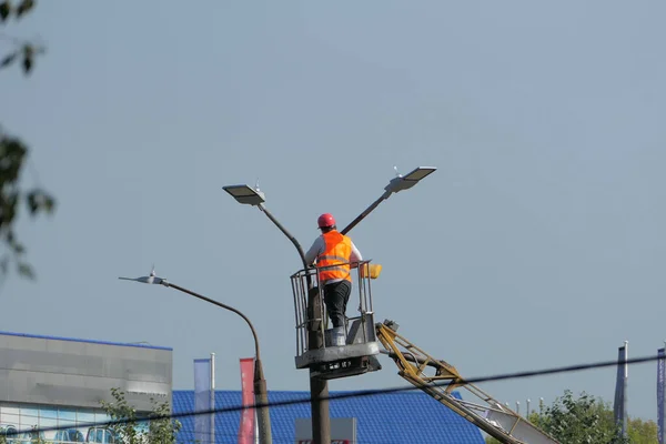 Street light. A worker in special clothes and a helmet repairs a street lamp on a city street. High quality photo