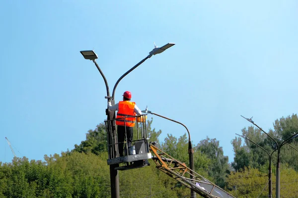 Sokak lambası. Özel elbiseli ve kask takan bir işçi sokak lambasını tamir ediyor. Yüksek kalite fotoğraf