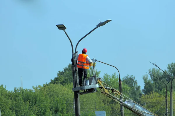 Sokak lambası. Özel elbiseli ve kask takan bir işçi sokak lambasını tamir ediyor. Yüksek kalite fotoğraf