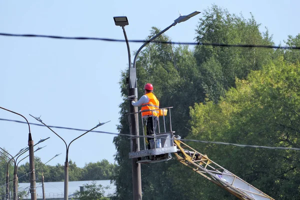 Street light. A worker in special clothes and a helmet repairs a street lamp on a city street. High quality photo