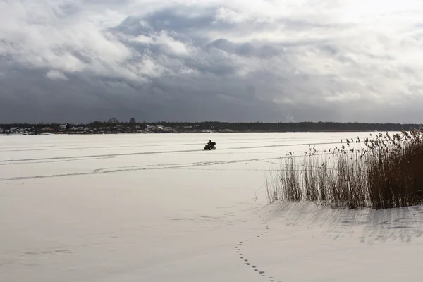 Hombre en ATV cabalgando en el río congelado . —  Fotos de Stock