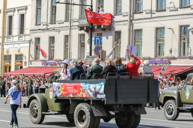 Bir kamyonun arkasından geçen insanlar.