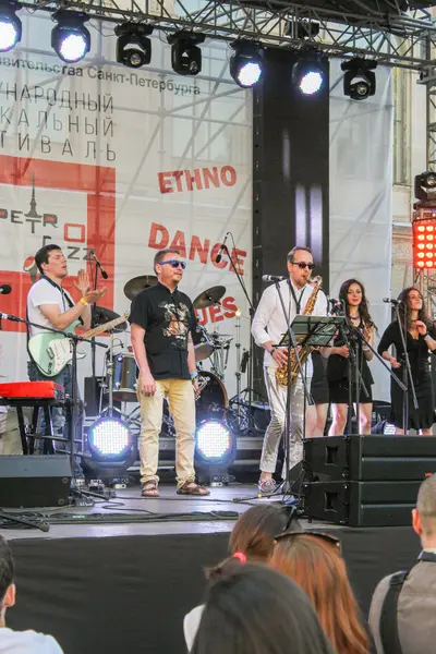 Müzisyenler beyaz projektörler ile sahnede.