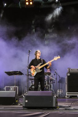 Dumanlı sahnede bir gitar ile şarkıcı.